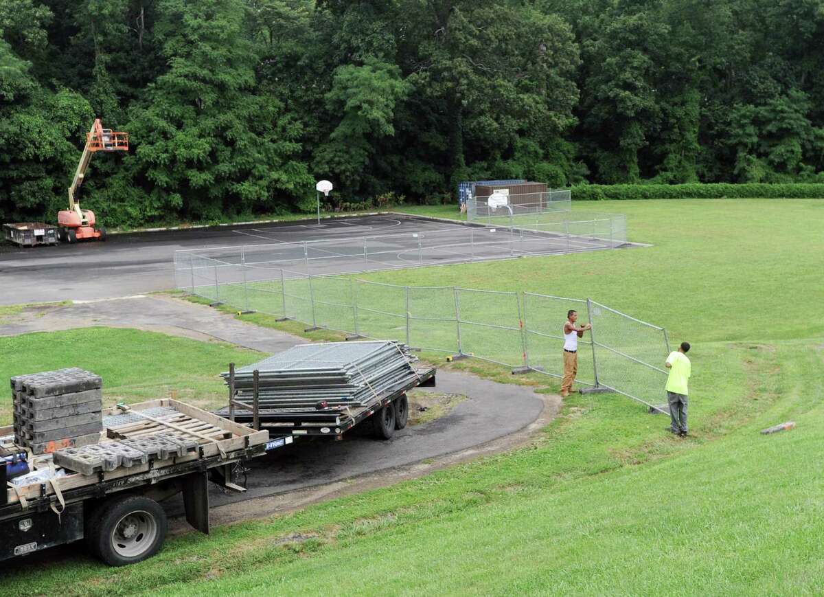 Workers from Total Fence Co. install fencing around the fields at Western Middle School in the Byram section of Greenwich, Conn., Thursday, Sept. 1, 2016. The fields have been closed by town officials after tests found elevated levels of lead and other toxins in the soil there.