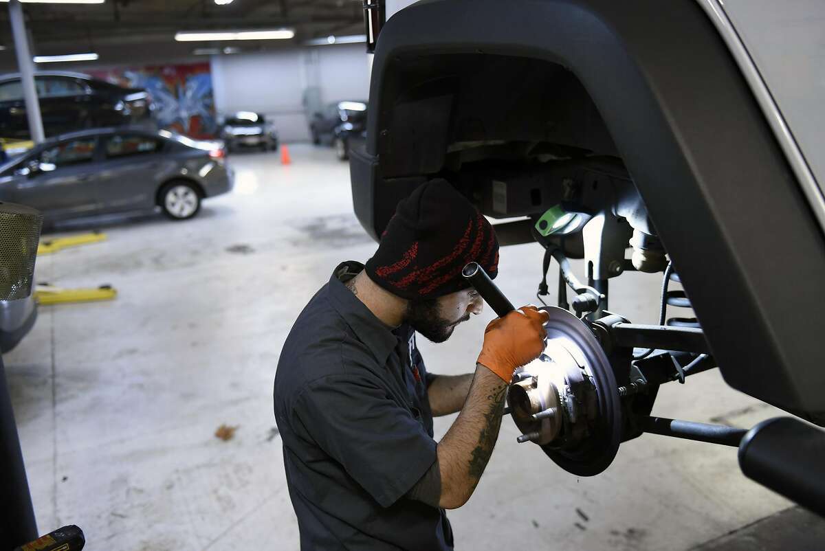 Automotive technician Gurgen Petrosyan works on replacing an axel seal on a customer's car in the repair garage at Shift's headquarters in South San Francisco CA, on Wednesday, December 14, 2016.