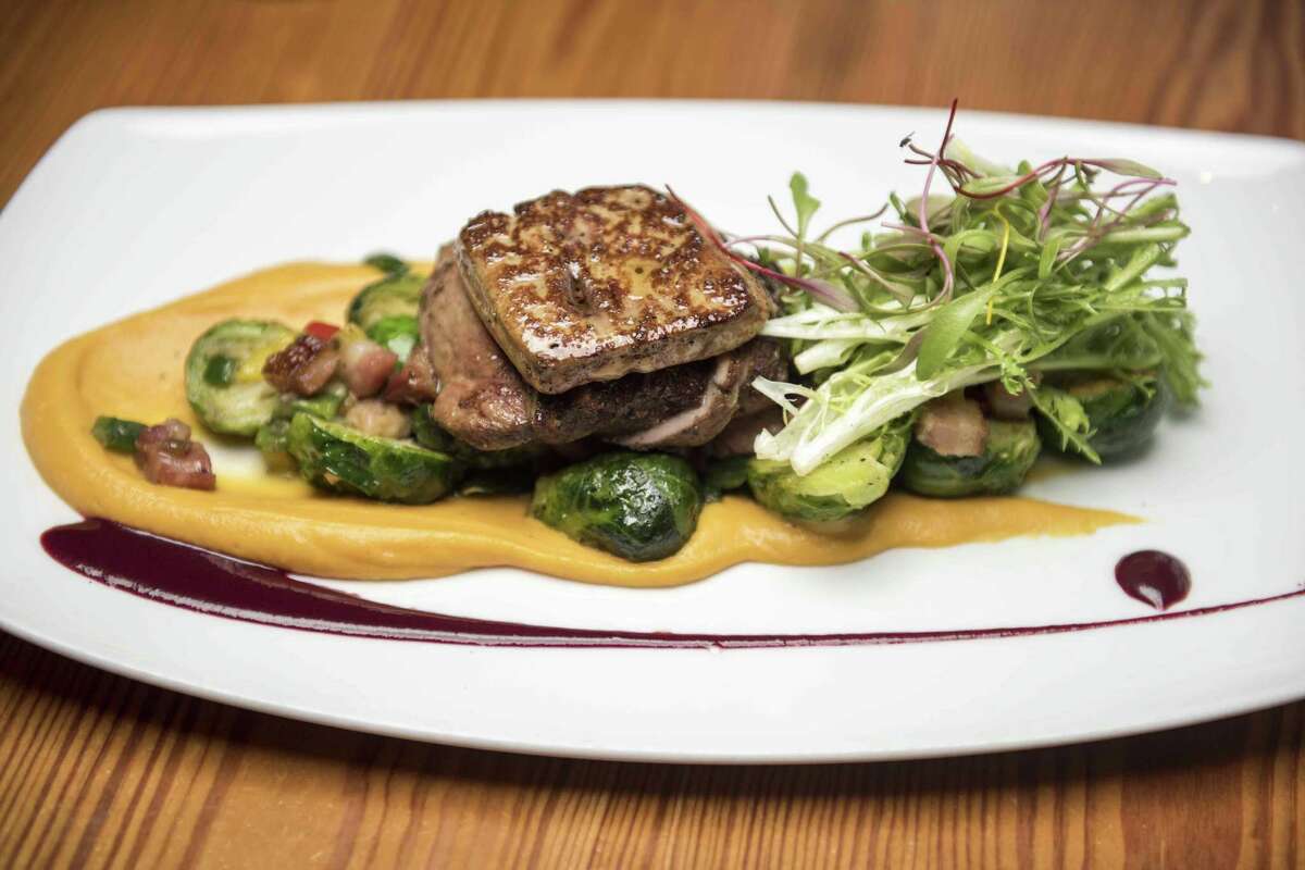 The duck and foie gras entree consists of grilled Szechuan peppercorn and five-spice crusted duck breast, seared foie gras, tri-colored peppers, Brussels sprouts with bacon, sweet potato puree and huckleberry gastrique.