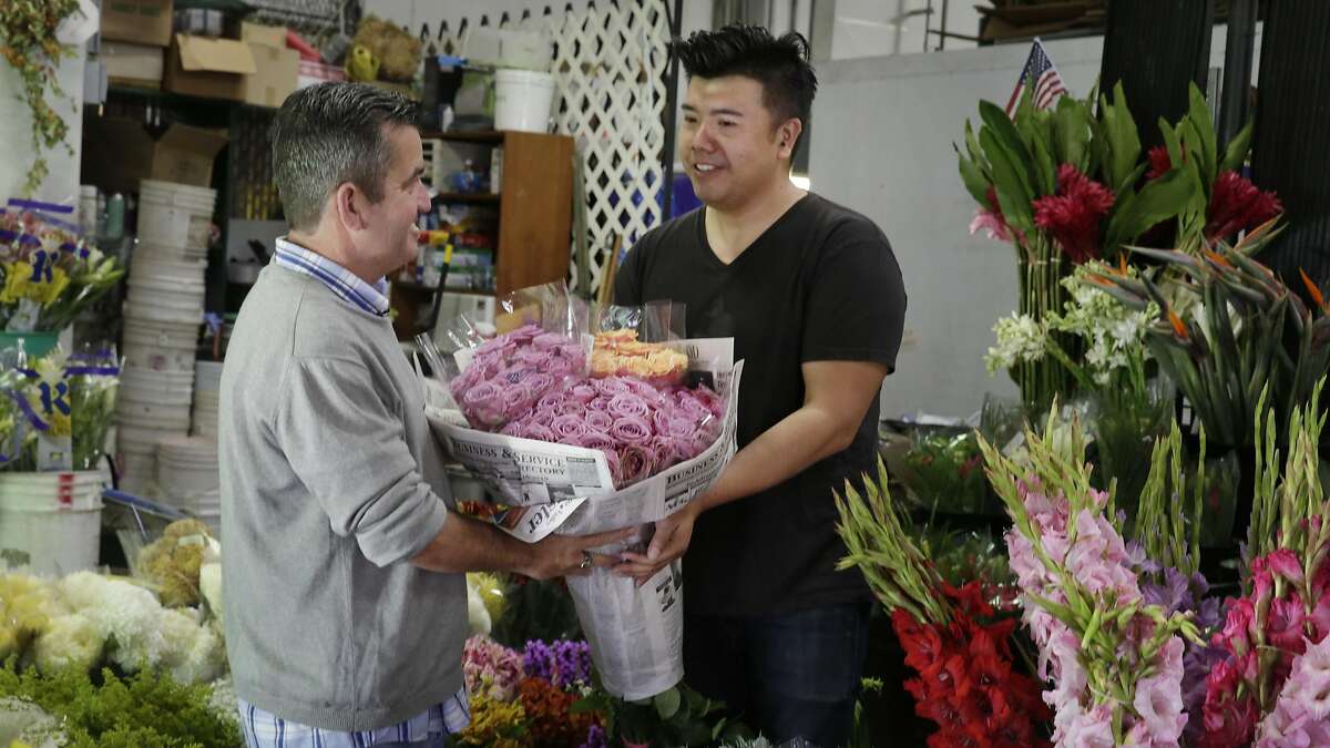 Joel Phmah, owner Piazza Wholesale, hands Darren Fanelli,activity director SteppingStone Mission Creek Day Health,, bouquets of flowers he donates to be used in an activity for the seniors at SteppingStone on Friday, October 21, 2016 in San Francisco, California.