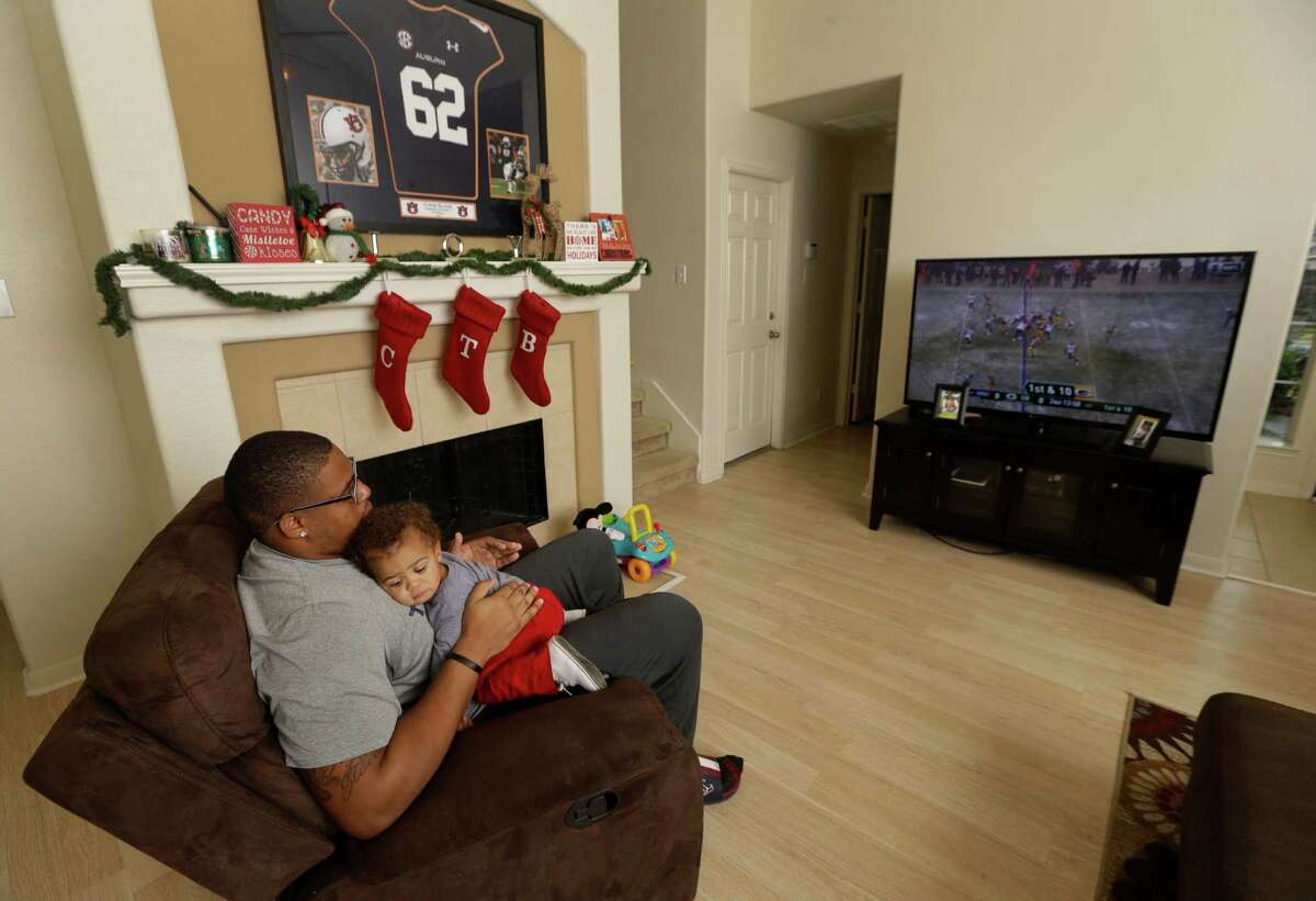 Texans practice squad player Chad Slade holds his 14-month-old son, Braxton Slade, while watching the Texans and Packers game on television at his home Sunday, Dec. 4, 2016, in Pearland. ( Melissa Phillip / Houston Chronicle )