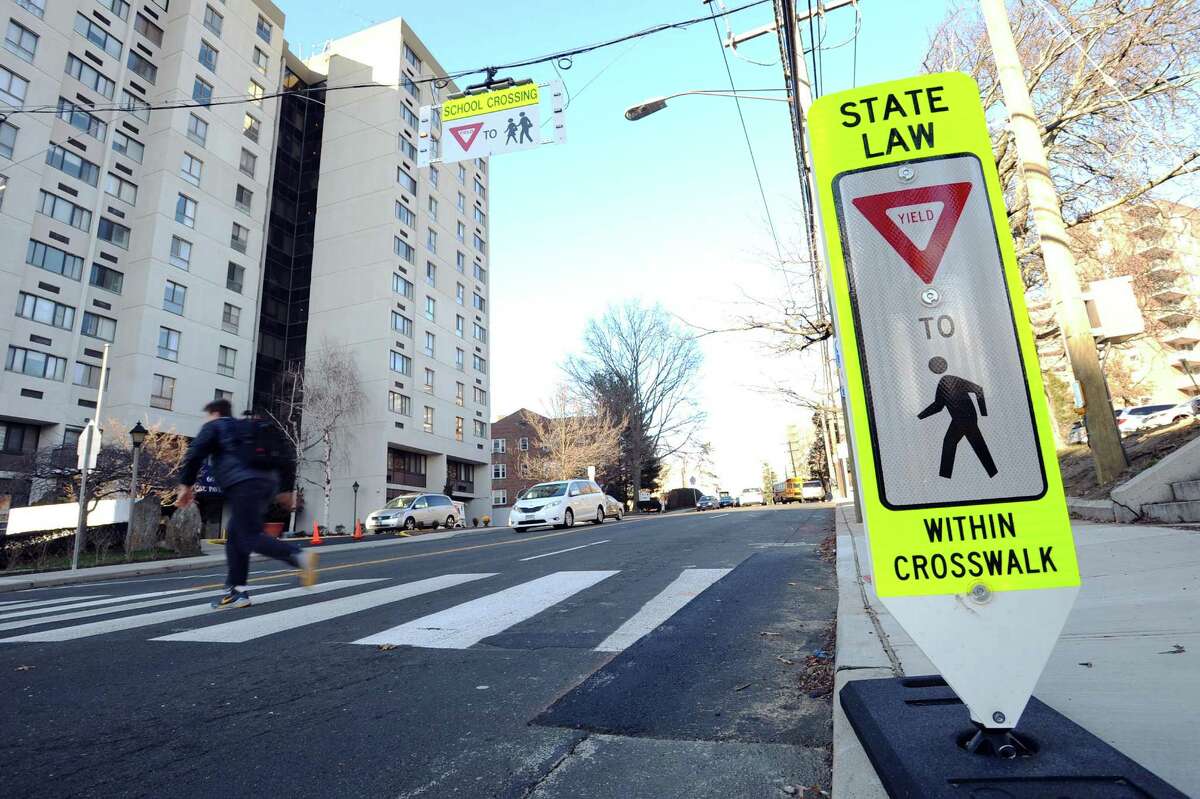 A student uses the crosswalk, which features a new flashing, hanging sign, outside Stamford High School in Stamford.