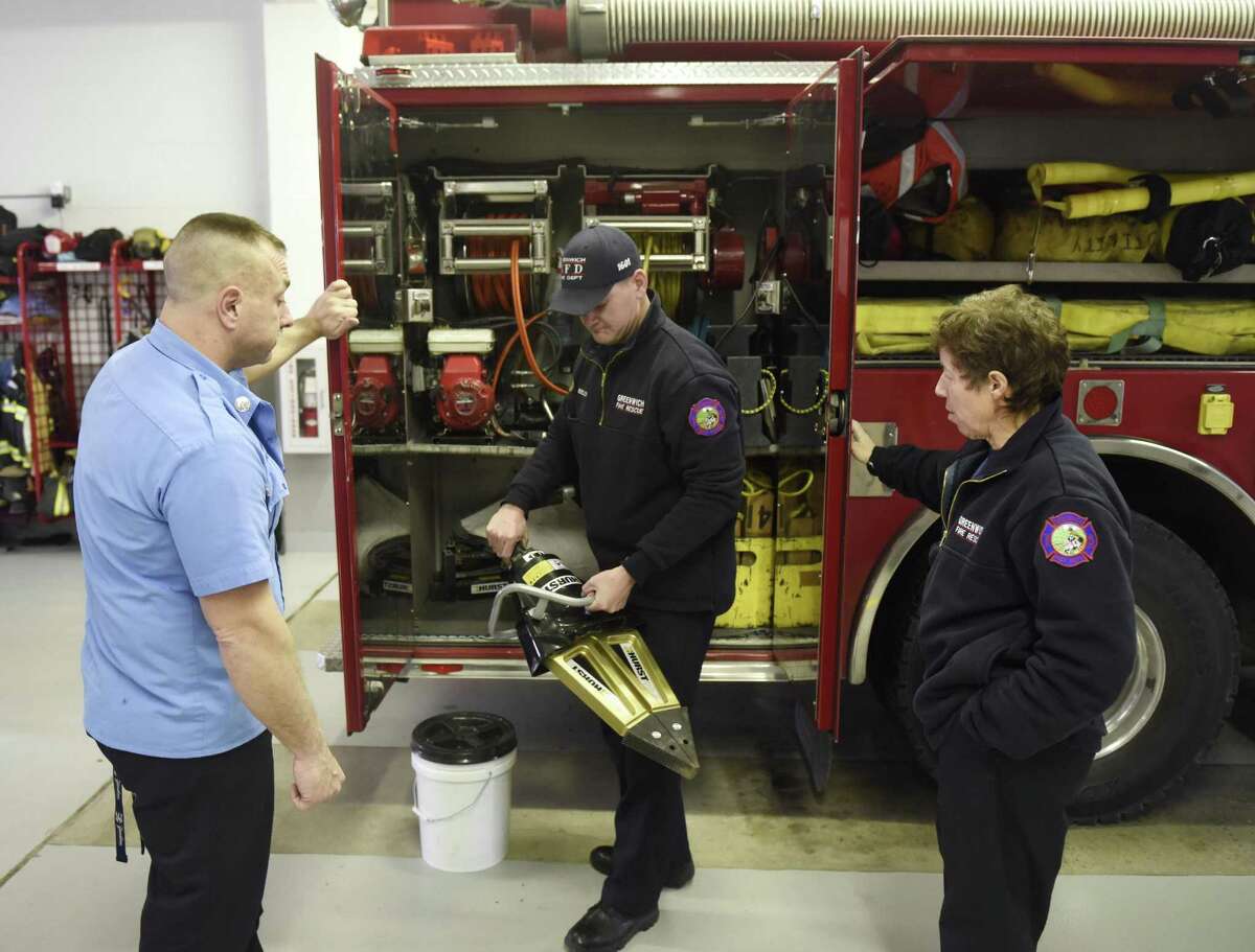 Firefighter Christopher Kelly, center, takes the Jaws of Life instrument out of the engine as Fire Lt. Dennis Frulla and firefighter Whitney Welch assist at the Glenville Fire Department in the Glenville section of Greenwich, Conn. Thursday, Dec. 15, 2016. At the end of November, the paid Greenwich fire departments began operating with a three-person crew instead of a four-person crew in an effort for the town to save money.