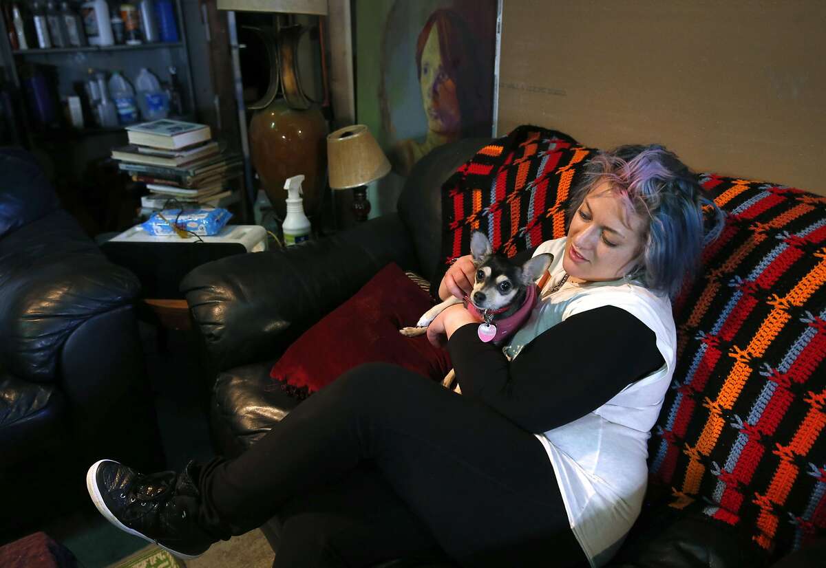 Erica Moulder pets her dog Penny inside a warehouse where she lives with other artists on Peralta Ave. in San Francisco, Calif. on Friday, Dec. 16, 2016. The group was handed an eviction notice several days after the deadly Dec. 2 Ghost Ship warehouse fire in Oakland.