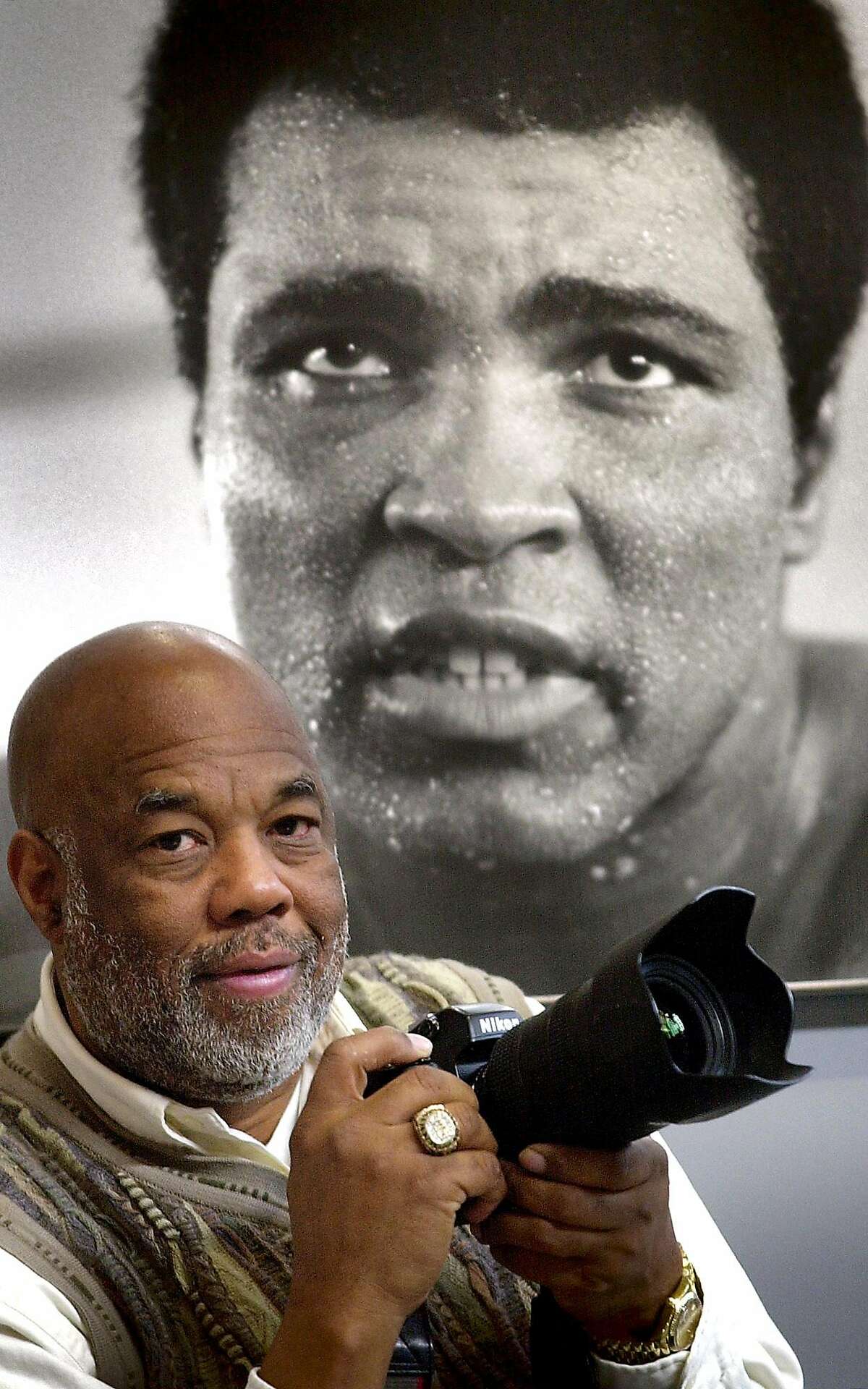 Photographer Howard Bingham stands next to a photo of Muhammad Ali, part of an exhibit of his works Friday, Jan. 18, 2002 at the Smithsonian's Arts and Industries Building in Washington. The exhibit of 123 photos that Bingham shot in Zaire in September and October 1974 around the time of Ali's storied fight with George Foreman., opens Saturday. (AP Photo/Kenneth Lambert) HOUCHRON CAPTION (01/19/2002): Photographer Howard Bingham stands Friday next to a photo of Muhammad Ali, part of an exhibit of his work at the Smithsonian Institution in Washington.
