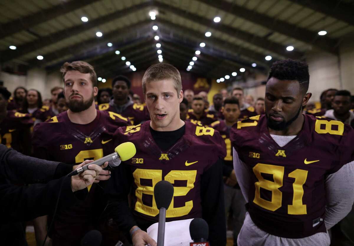 University of Minnesota wide receiver Drew Wolitarsky, flanked by quarterback Mitch Leidner, left, and tight end Duke Anyanwu stands in front of other team members as he reads a statement on behalf of the players in the Nagurski Football Complex in Minneapolis, Minn., Thursday night, Dec. 15, 2016. The players delivered a defiant rebuke of the university's decision to suspend 10 of their teammates, saying they would not participate in any football activities until the school president and athletic director apologized and revoked the suspensions. If that meant they don't play in the upcoming Holiday Bowl against Washington State, they appeared poised to stand firm. (Jeff Wheeler/Star Tribune via AP) ORG XMIT: MNMIT201