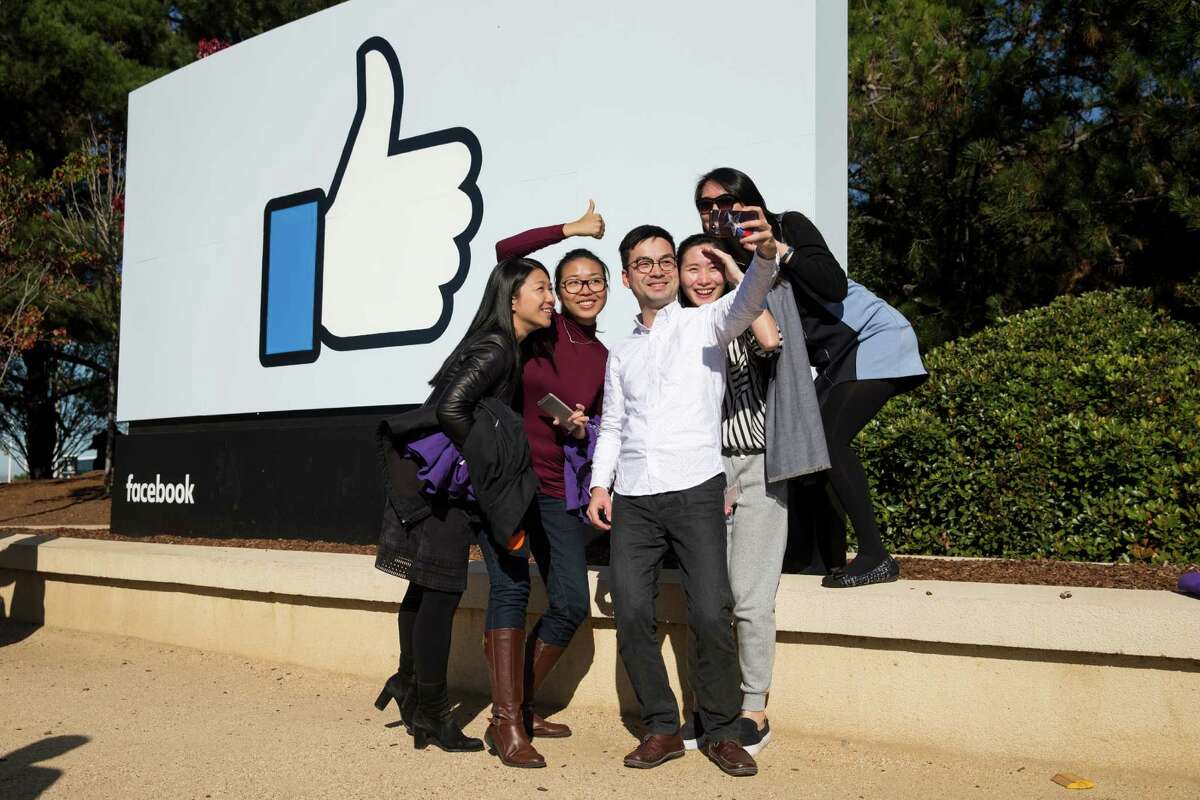 Tourists take a selfie in front of a Facebook sign at the company's headquarters in Menlo Park, Calif.﻿