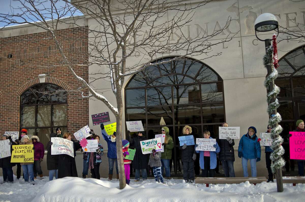 A group rallies in front of the Mackinac Center on Saturday in downtown Midland. More than 30 people met at the corner of Gordon and Main streets for a rally and march to celebrate the resistance of policy and intolerance based on fear and hate. The event was hosted by the Women of Michigan Action Network (W.O.M.A.N.), a local group for positive change and resistance formed in response to the election of Donald Trump. The group marched between Gordon and Ashman streets and chanted slogans including, "Show me what democracy looks like, this is what democracy looks like," and "Love not hate makes America great," to name a few. The group also sang, "America the Beautiful" and "This Land Is Your Land."