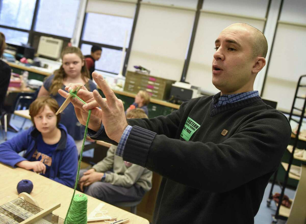 Local artist Ruben Marroquin demonstrates technique for weaving with a loom to students at Eastern Middle School in Greenwich.