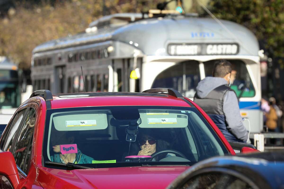 An Lyft car is seen on Market Street with the F train behind it on Friday, December 17, 2016 in San Francisco, Calif.