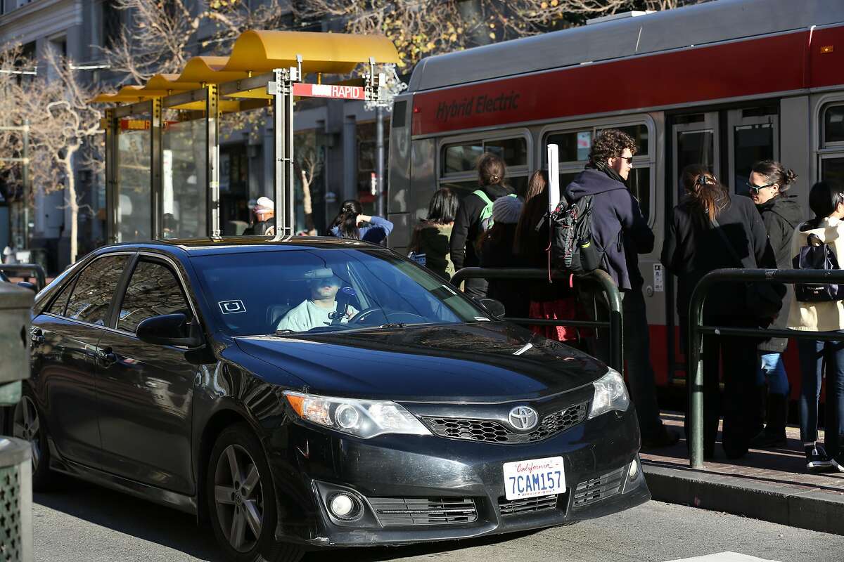 An Uber car is seen next to a Muni stop on Market Street on Friday, December 17, 2016 in San Francisco, Calif.