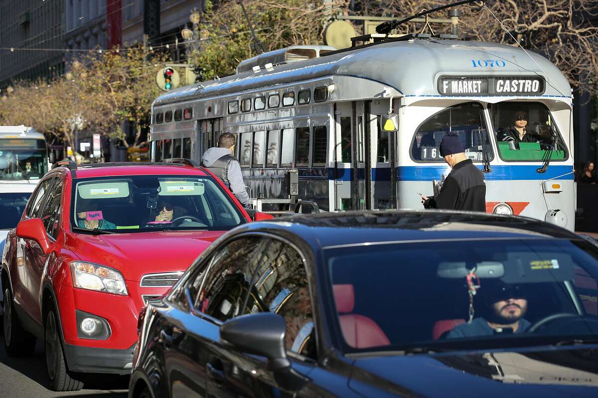 An Lyft car is seen on Market Street with the F train behind it on Friday, December 17, 2016 in San Francisco, Calif.