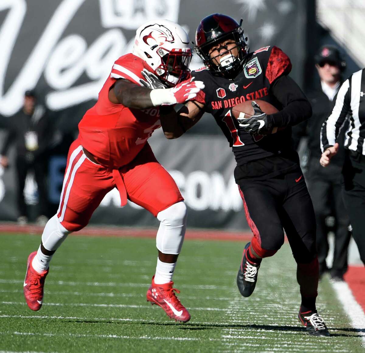 San Diego State's Donnel Pumphrey runs past UH's Matthew Adams on his way to setting the NCAA rushing mark Saturday.