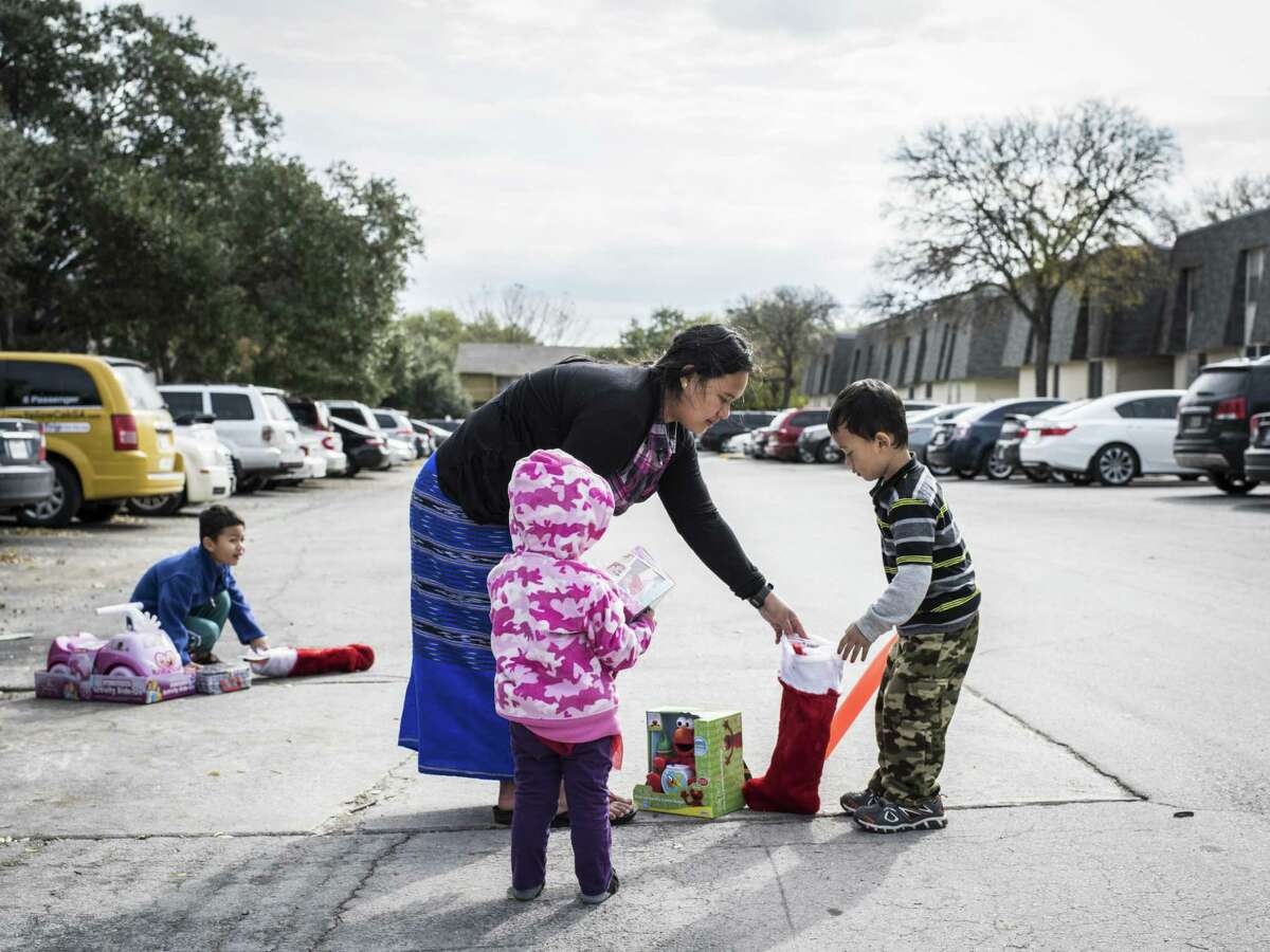 Soemeh helps her children Boe, 6, (left), Elizabeth, 2, (center), and Moriko, 4, gather their toys during the fourth toy giveaway for refugee children put on by the Bexar County Young Tejano Democrats in San Antonio on Sunday. Soemeh and her children are refugees from Burma. The group of volunteers went to various apartments where refugee families have settled in San Antonio.