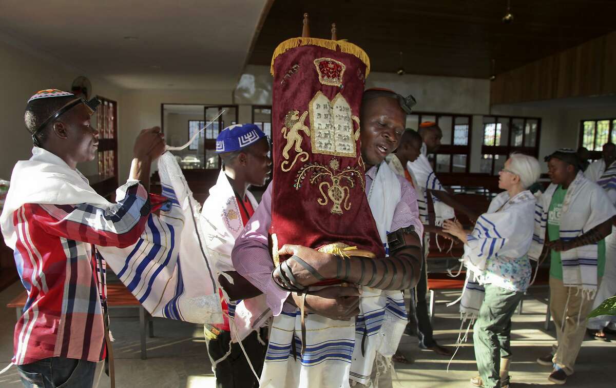 In this photo taken Thursday, Nov. 3, 2016, Ugandan Jew Israel Siriri, center, carries the Torah during prayers at the new Stern Synagogue in Mbale, eastern Uganda. The synagogue, built largely with money donated by Americans, is a source of pride for hundreds of Ugandan Jews known locally as the Abayudaya, who have tenaciously maintained their belief despite the prejudice they have suffered over the years in this Christian-dominated country. (AP Photo/Stephen Wandera)