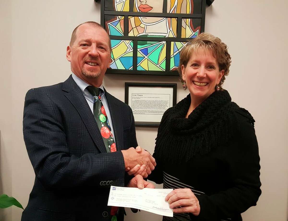 Scott Withrow, vice president at Saginaw Bay Underwriters, presents a check to Kathy Allen, executive director of Personal Assistance Options.