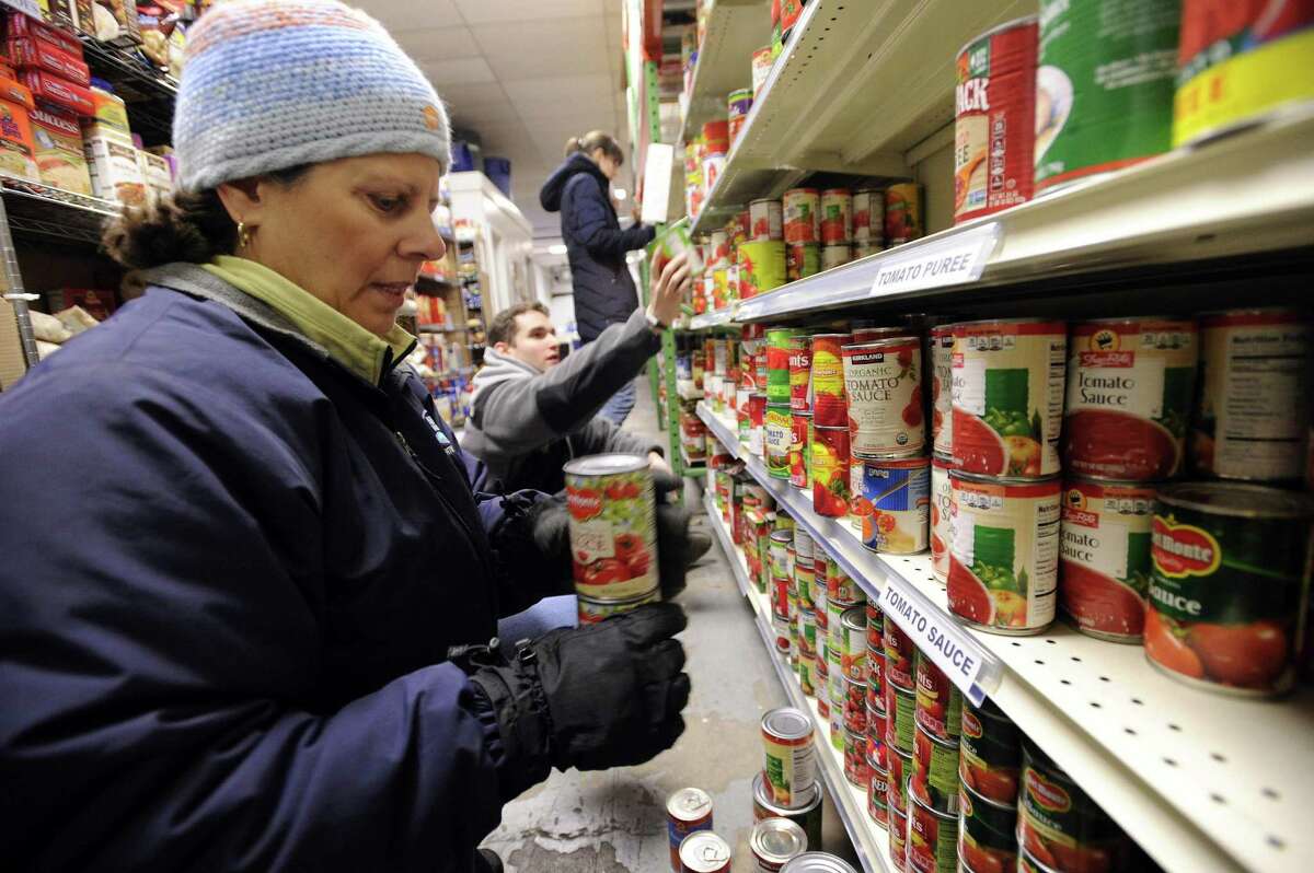 Maria Santanna, a CFO with Nestle Readyfresh Division, checks expiration dates and sorts canned goods along with a couple dozen company volunteers at the Food Bank of Lower Fairfield County in Stamford on Dec. 16, 2016.