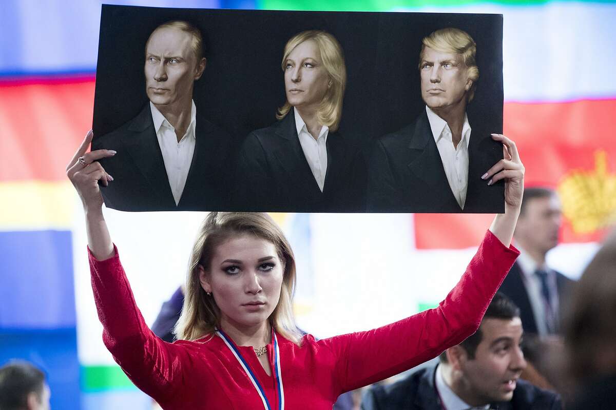 A journalist holds a poster with portraits of Russian President Vladimir Putin, left, France's far-right National Front president Marine Le Pen, center, and President-elect Donald Trump prior to Russian President's annual news conference in Moscow, Russia, Friday, Dec. 23, 2016. (AP Photo/Pavel Golovkin)