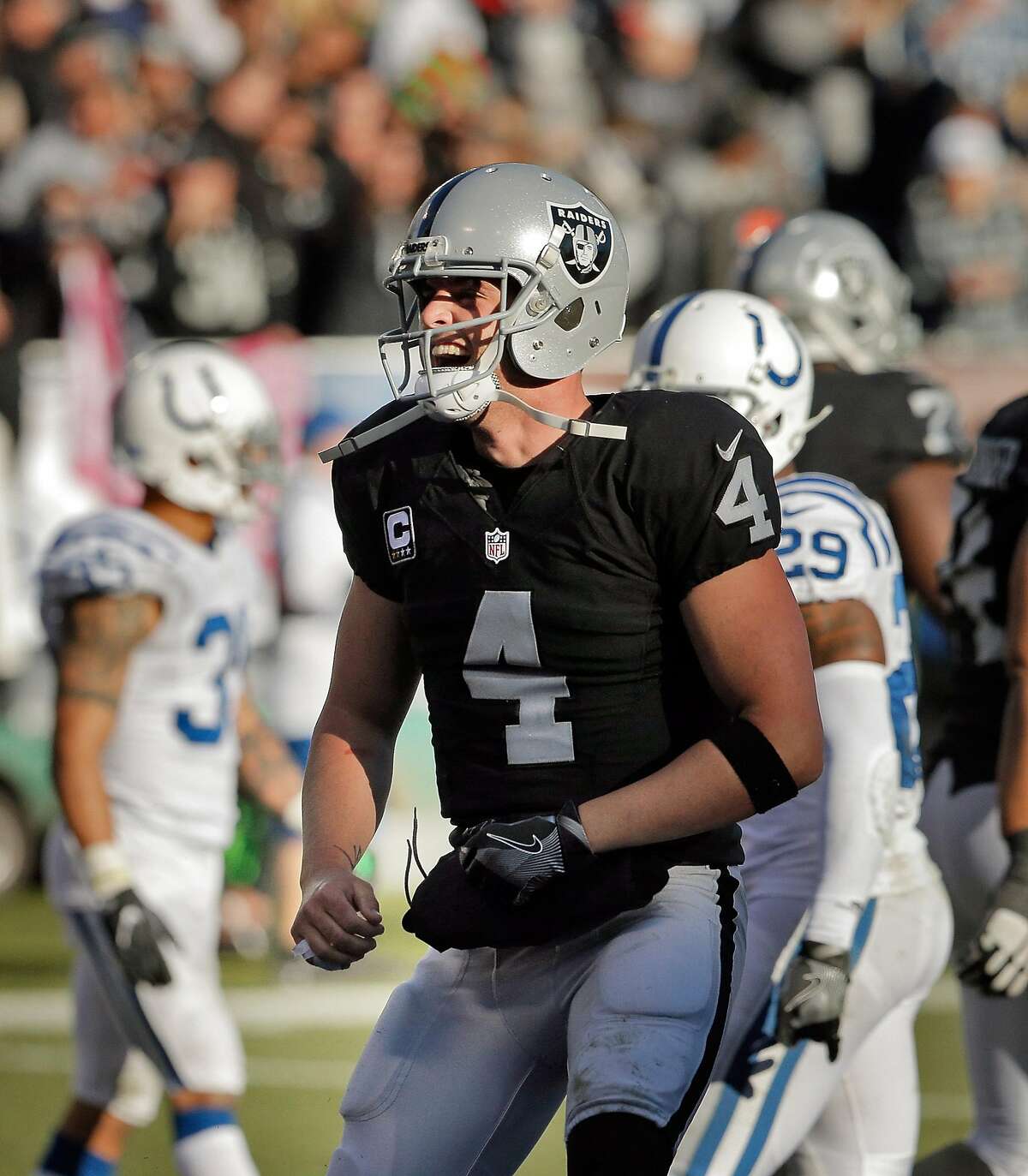 Derek Carr (4) celebrates a DeAndre Washington (33) touchdown in the third quarter as the Oakland Raiders played the Indianapolis Colts at the Oakland Coliseum in Oakland, Calif., on Saturday, December 24, 2016. The Raiders won the game 33-25, but lost quarterback Derek Carr to injury.