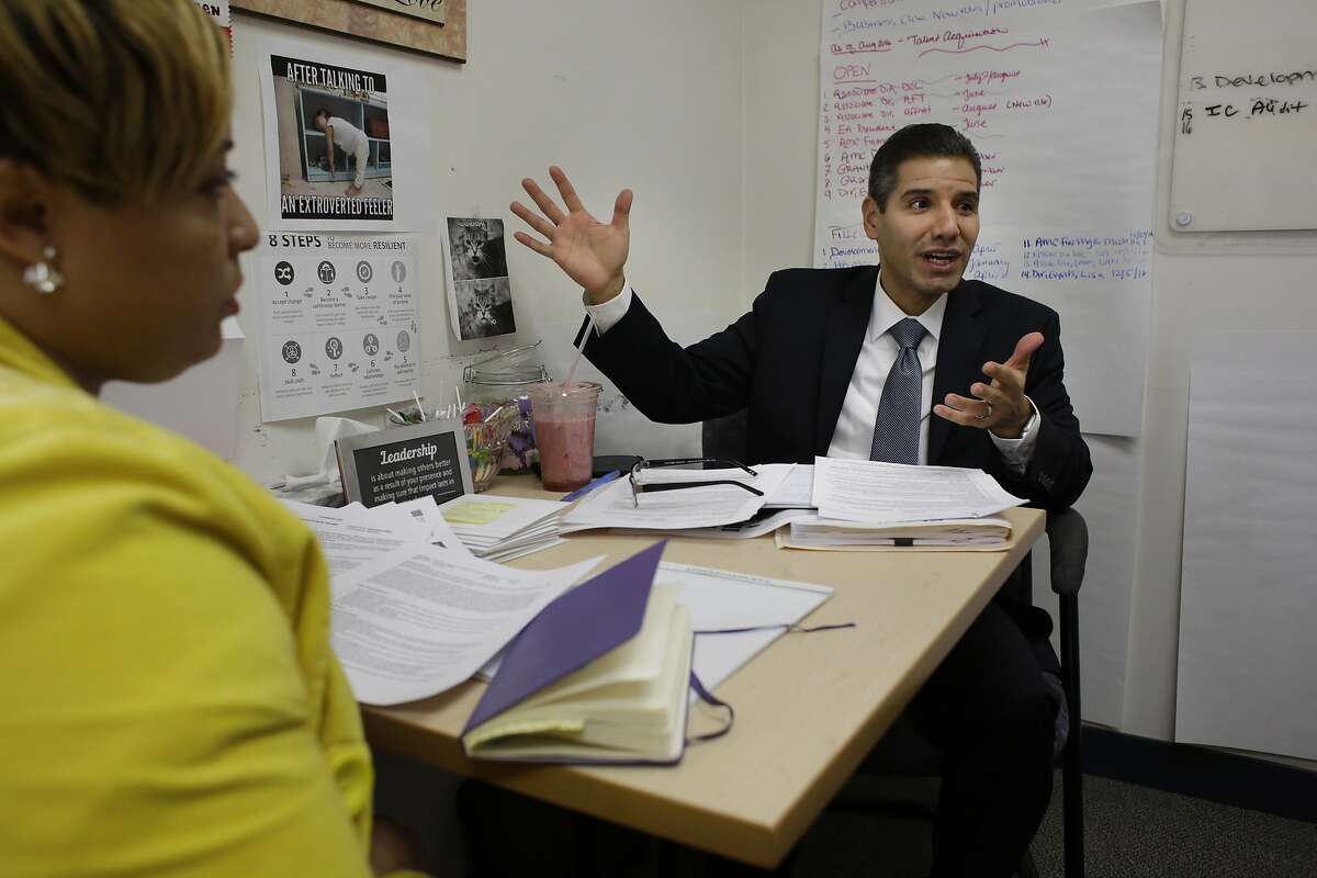 In this Nov. 22, 2016, photo John Valverde, right, speaks during a meeting while seated next to Chiffawn Johnson, left, a talent acquisition manager and human resources generalist at YouthBuild USA, Inc., in Somerville, Mass. In January of 2017 Valverde is to take over as CEO of the organization that helps young, low-income inner-city dropouts reclaim their lives. (AP Photo/Steven Senne)