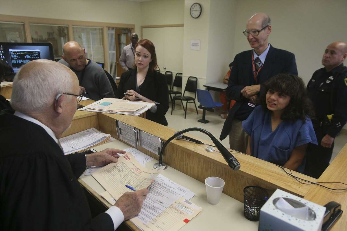 Visiting Judge Olin Strauss speaks to a defendant standing in front of her attorney, Jim Oltersdorf, at “jail court” at the Bexar County Adult Detention Center.