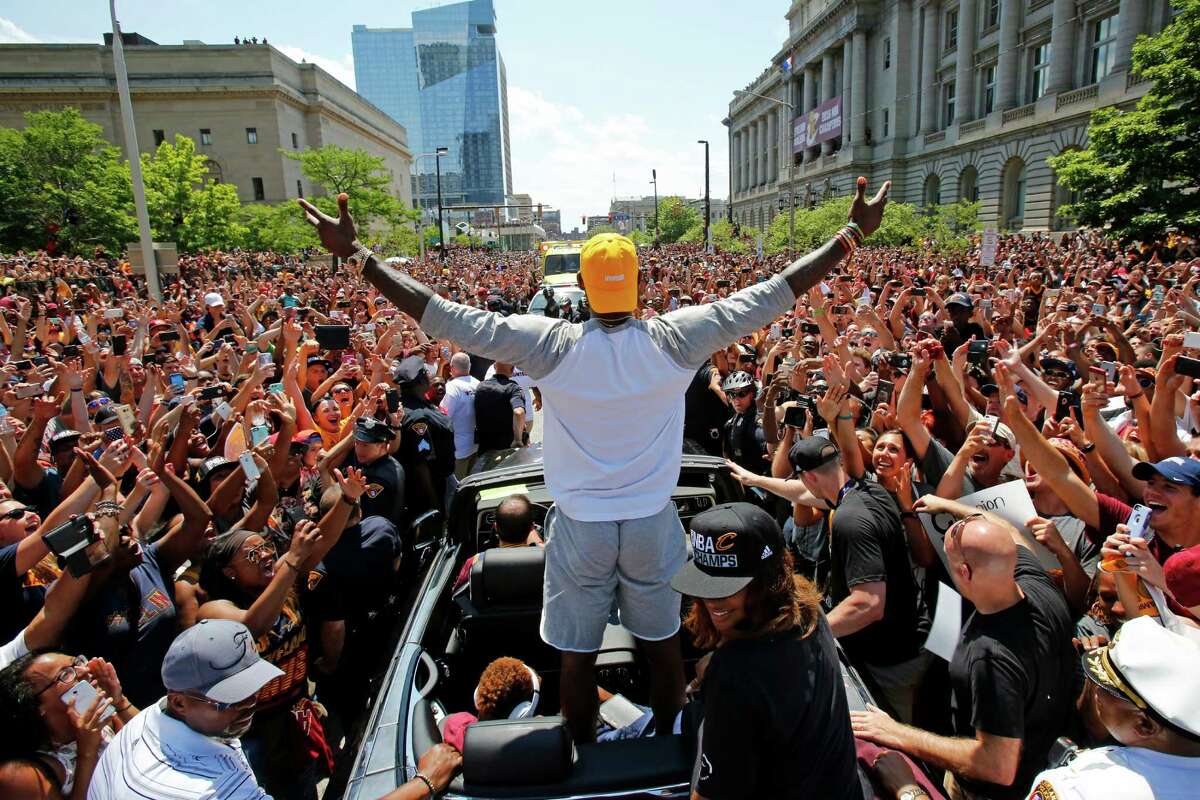 FILE - In this June 22, 2016 photo, Cleveland Cavaliers' LeBron James, center, stands in the back of a Rolls Royce as it makes its way through the crowd lining the parade route in downtown Cleveland, celebrating the basketball team's NBA championship. On Tuesday, Dec. 27, James, who ended 52 years of sports heartache by bringing Cleveland a championship and used his superstar platform to address social causes, was chosen as The Associated Press 2016 Male Athlete of the Year. (AP Photo/Gene J. Puskar, File)