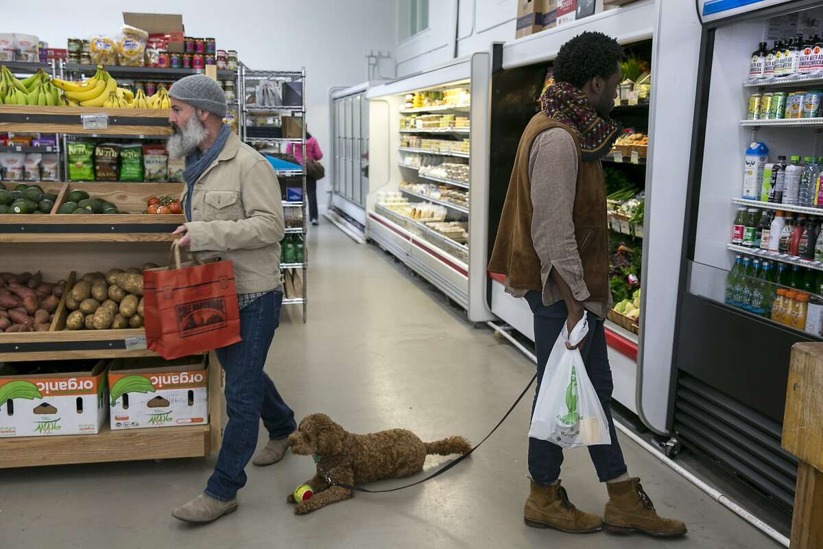 From right: Lowell Caulder with his dog Moses check out the bottled drinks as Bradley Burch makes his way to the produce section at Luke's Local on Tuesday, Dec. 27, 2016 in San Francisco, Calif. Caulder and Burch both live in the neighborhood.