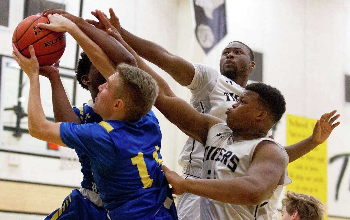 Klein's Bryce Richardson (11) grabs a rebound out of reach from the outstretched hands of Conroe forwards Quentin Brown (12) and Lavery Shepherd (21) during the third quarter of a non-district high school boys basketball game at the Conroe Christmas Classic Tuesday, Dec. 27, 2016, in Conroe. Klein defeated Conroe 50-46.
