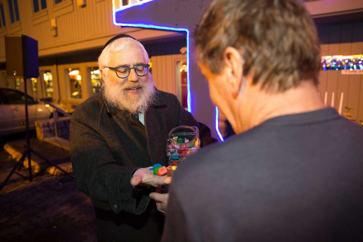Rabbi Yehoshua Hecht hands out dreidels before the menorah lighting to celebrate the fourth night of Hanukkah at Stew Leonards in Norwalk, Conn. on December 27, 2016.