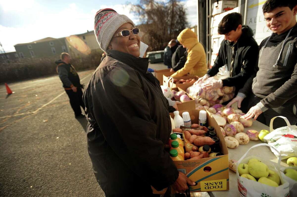 Ketena Charles, of Bridgeport, smiles as she carries a box of food from the Monthly Mobile Food Pantry on Jane Street in Bridgeport, Conn. on Wednesday, December 28, 2016. The pantry is staffed by three groups of volunteers making up The Emmaus Partnership.