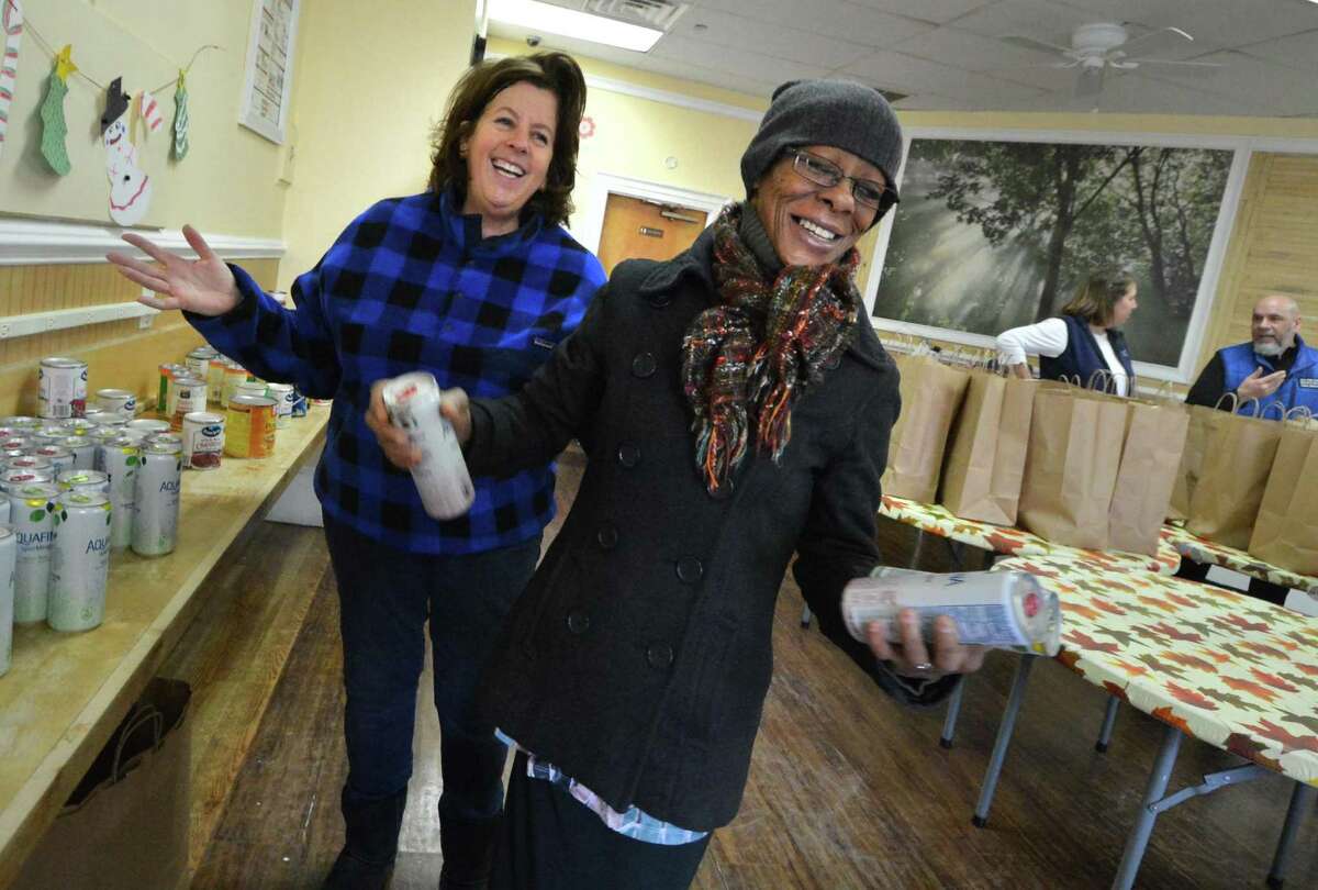 Volunteer Carol Cheswick from the First Congregational Church of Darien helps Chyretta Robinson fill her bag with some drinks to make a complete Christmas dinner from the the Open Door Shelter in Norwalk. More than 125 families will benefit from the program.