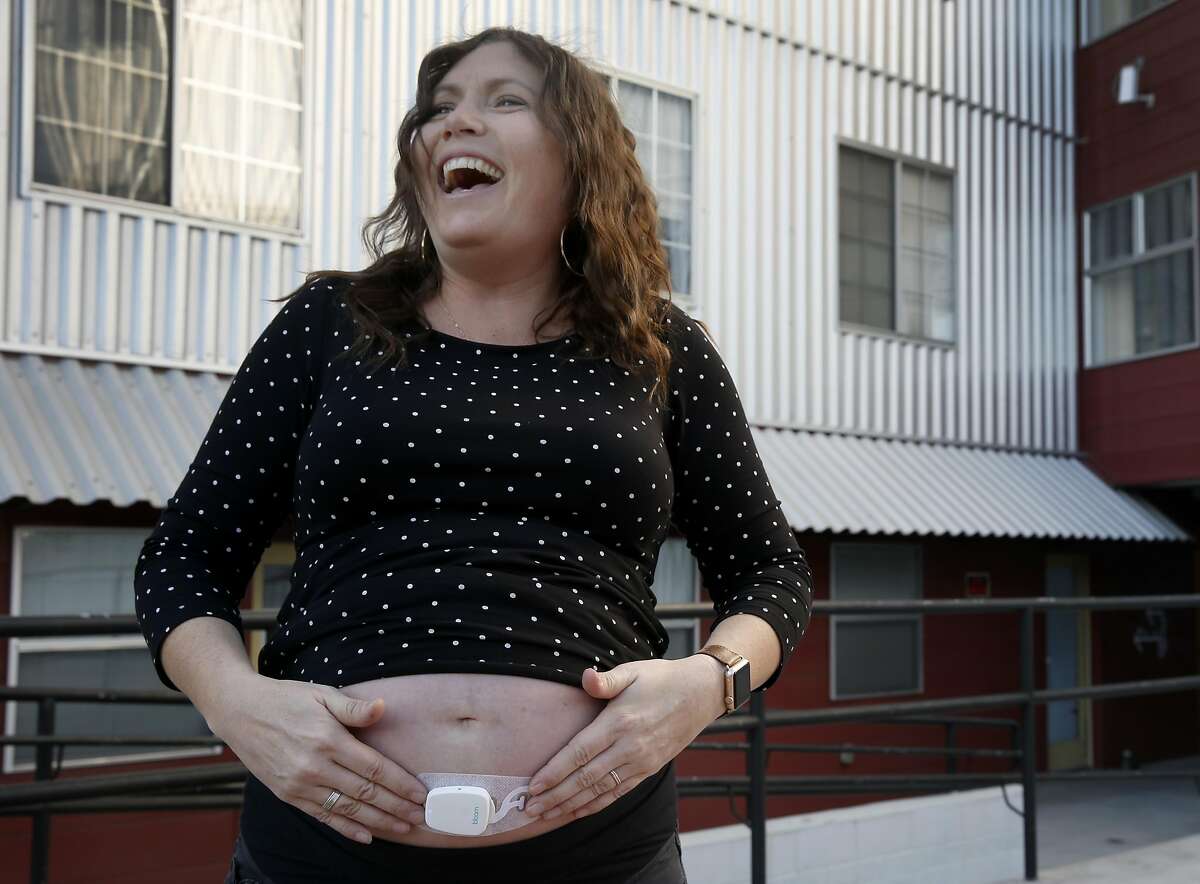 Molly Cruit laughs after attaching a Bloomlife pregnancy contraction sensor below her belly button in San Francisco, Calif. on Thursday, Dec. 29, 2016. The Bloomlife sensor monitors contractions in the womb of expectant mothers.