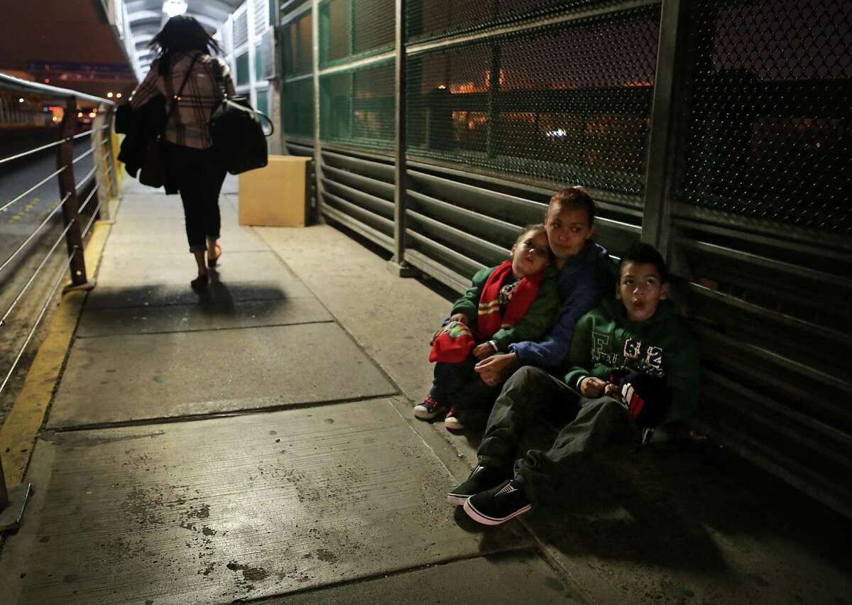 Alejandra Flores, from Honduras, huddles with her sons Alexande Josue Romero, 3, and Brision Josue Romero, 10, on the Hidalgo International Bridge in the early hours on Tuesday, Dec. 27, 2016, hoping to be let in the U.S. after a 22 day journey from their home in Honduras, spending Christmas on the road.