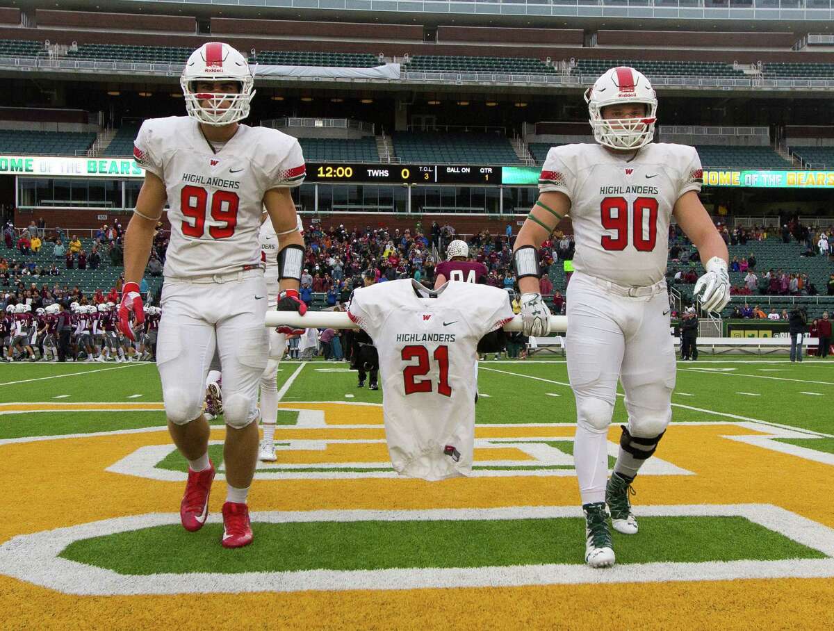 The Woodlands defensive lineman Michael Purcell (99) and Zachary Loane (90) carry the jersey of linebacker Grant Milton (21), who was named an honorary captain, before a Division I Region II-6A final game against Round Rock at McLane Stadium Saturday, Dec. 3, 2016, in Waco. Milton suffered a serious head injury during the team's Nov. 26 win over Austin Bowie in a UIL Class 6A Division I regional semifinal playoff game at Baylor's McLane Stadium. He was taken to a Waco hospital to have emergency surgery where he remains in a medically induced coma.