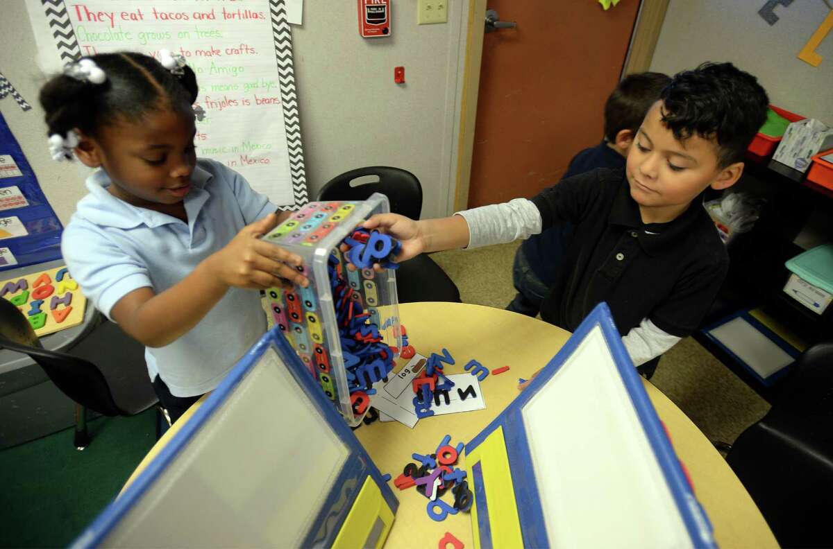 Malachi Rimirez puts magnetic alphabet letters in a container while Kamyle Martin dumps them out at Dowling Elementary on Friday. The letters are part of a learning tool that was purchased by the student's teacher Marissa Phillips who used a crowdfunding website to raise money for school supplies. Photo taken Friday, December 09, 2016 Guiseppe Barranco/The Enterprise