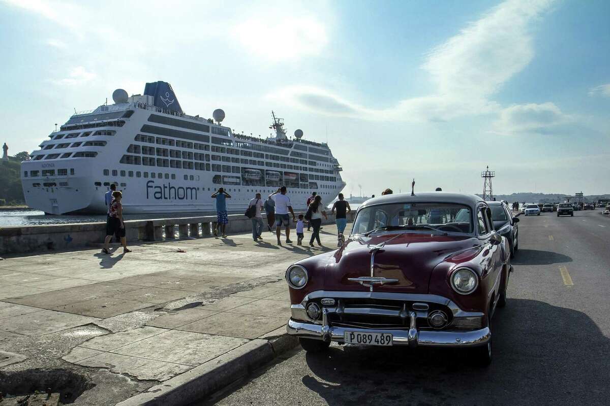 Vintage American cars in Havana serving as taxis await possible fares disembarking the 704-passenger Fathom Adonia.
