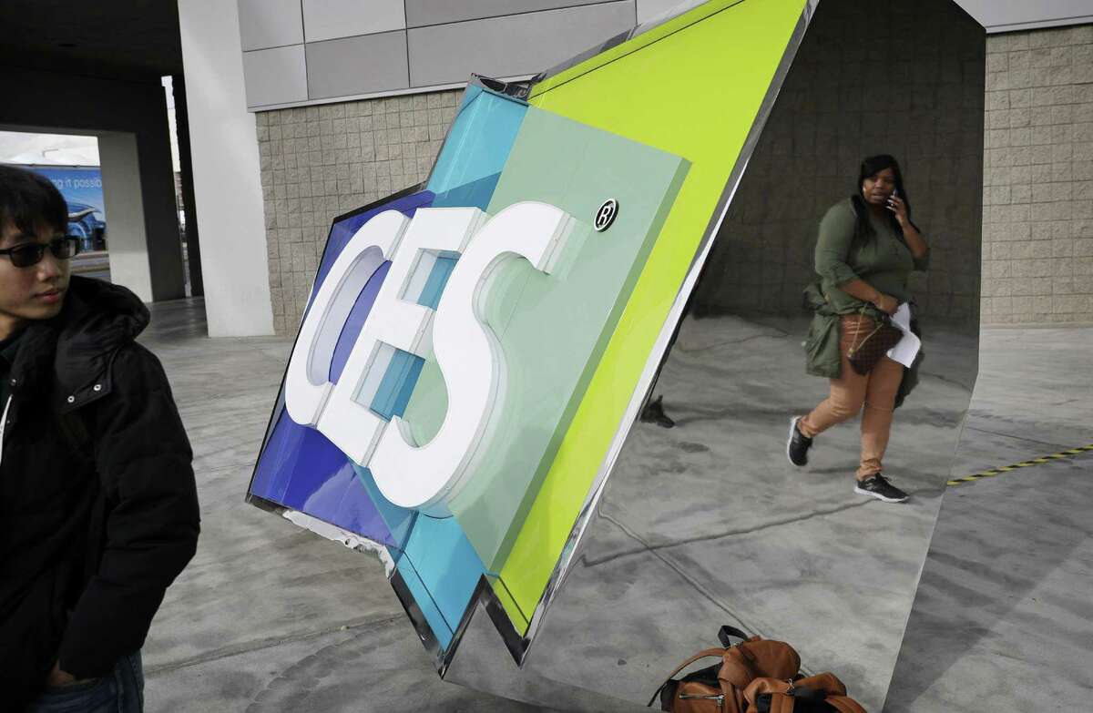 People walk by a sign during setup Tuesday for the annual CES tech show.