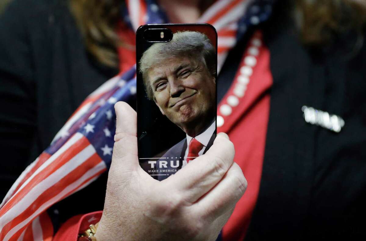 FILE - In this Thursday, Sept. 29, 2016, file photo, a woman holds up her cell phone before a rally with then presidential candidate Donald Trump in Bedford, N.H. President-elect Trump tweeted Tuesday that North Korea wonÂ?’t develop a nuclear weapon capable of reaching parts of the United States, but itÂ?’s possible it already has. After five atomic test explosions and a rising number of ballistic missile test launches, many experts believe that North Korea can arm short- and mid-range missiles with warheads that put Guam at risk. (AP Photo/John Locher, File)