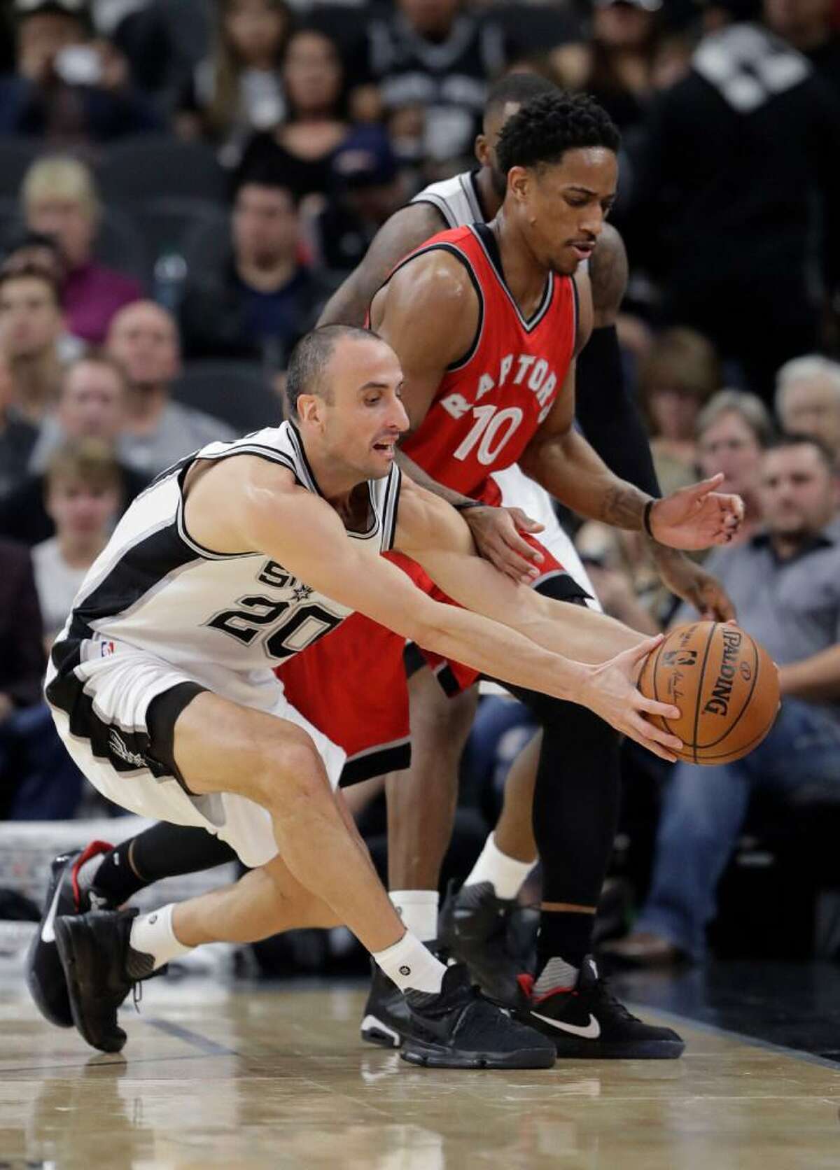 San Antonio Spurs guard Manu Ginobili (20) and Toronto Raptors guard DeMar DeRozan (10) chase a loose ball during the first half of the Spurs victory Tuesday at the AT&T Center.