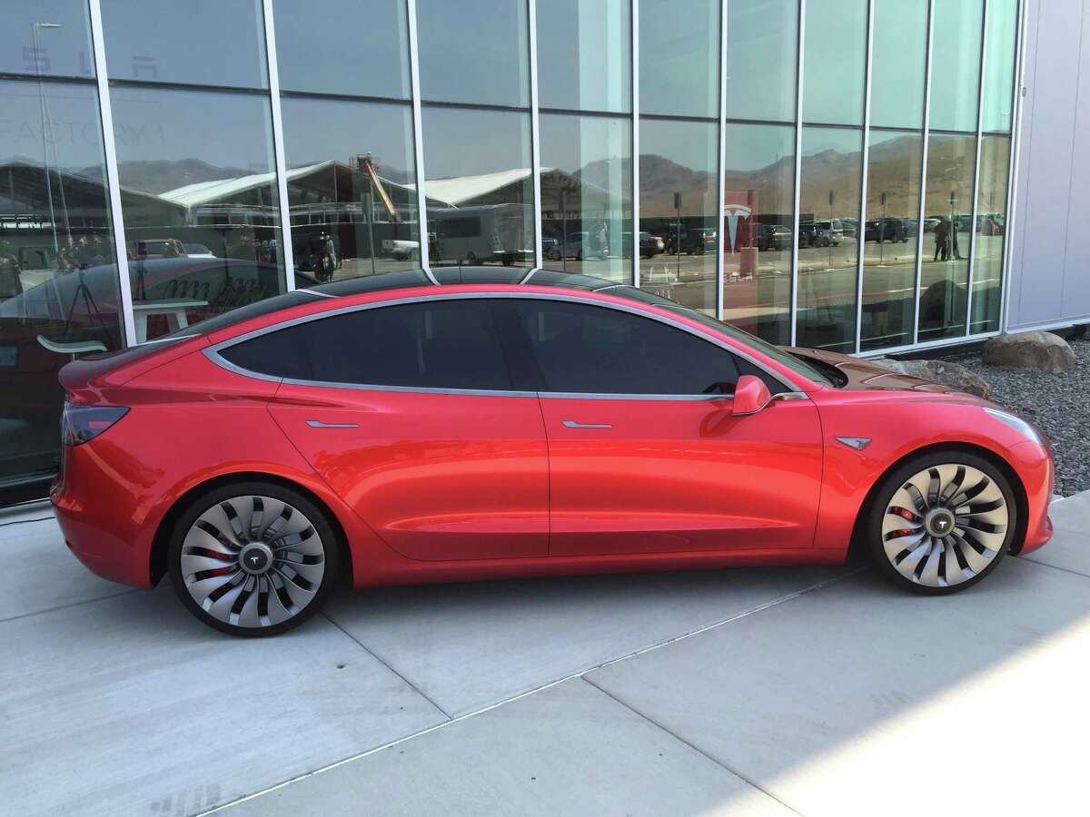 A prototype of the $35,000 Tesla Motors Model 3 sits outside the company’s Gigafactory in Nevada. The first battery cells rolled off production lines at the Gigafactory on Wednesday. The battery cells will power the company’s energy storage products and, before long, the Model 3 electric car.