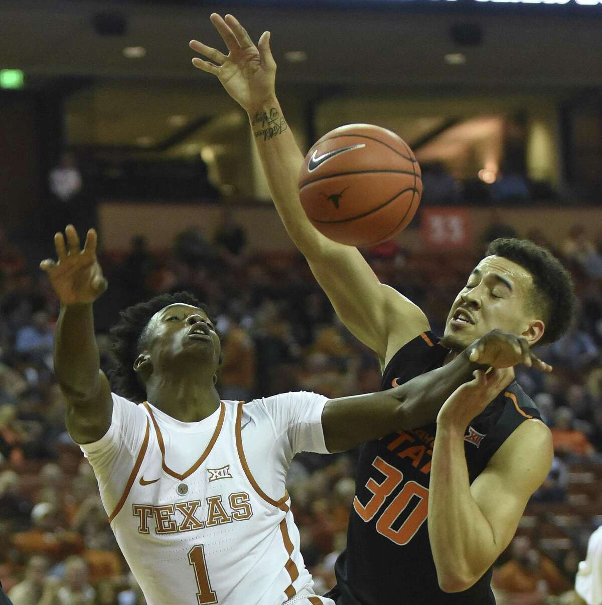 Andrew Jones (1) of Texax and Jeffrey Carroll (30) of Oklahoma State battle for a loose ball during Big 12 action in Austin on Wednesday, Jan. 4, 2017.