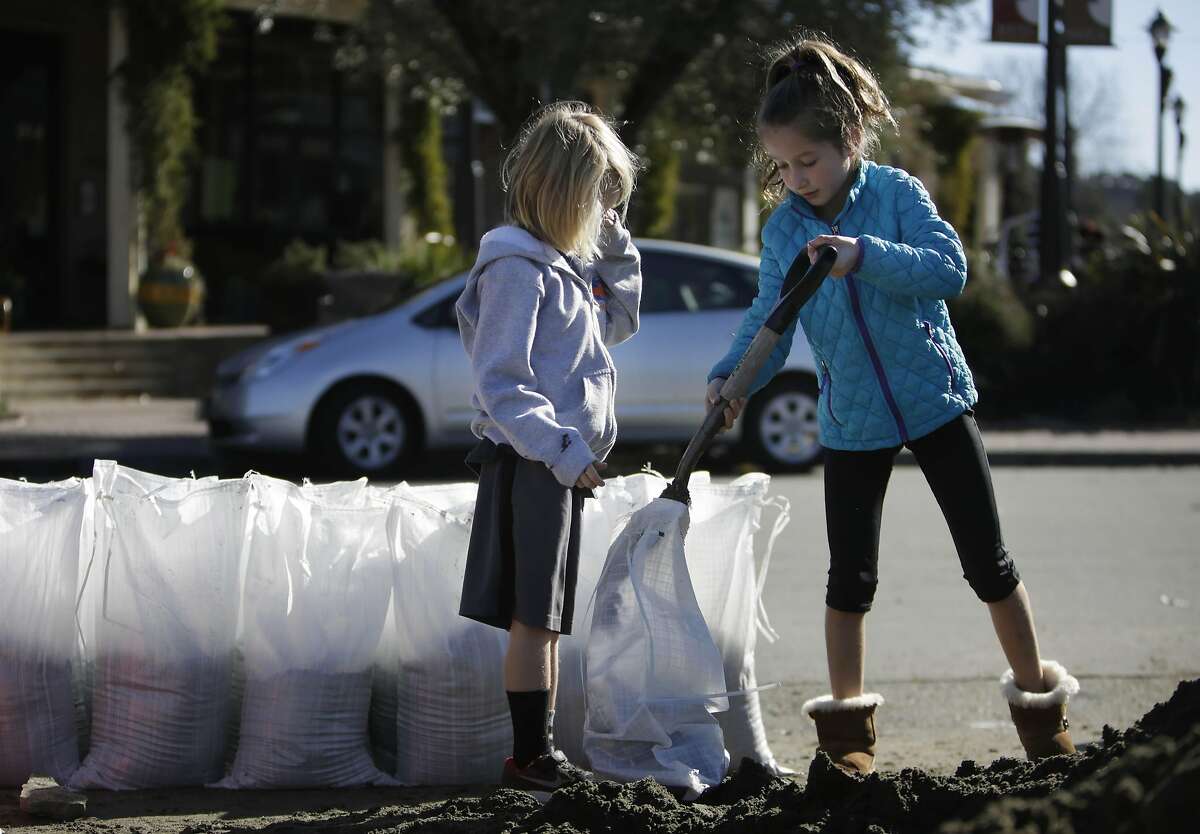 Siblings Isaac (l to r) Holden, 6 and Liat Holden, 9, help their mother as they fill sandbags for their home along Sunny Hills Drive on Thursday, January 5, 2017 in San Anselmo, Calif.