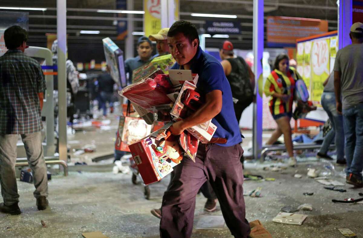 A man runs with toys as a store is ransacked by a crowd in the port of Veracruz, Mexico, Wednesday Jan. 4, 2017. Protests over a sharp gasoline price hike erupted into looting of gas stations and stores in various parts of Mexico on Wednesday, with dozens of businesses reportedly sacked. In the Gulf coast state of Veracruz, store guards were overrun by crowds who carried off clothing, toys, food, washing machines, televisions, DVD players and refrigerators.(AP Photo/Ilse Huesca)