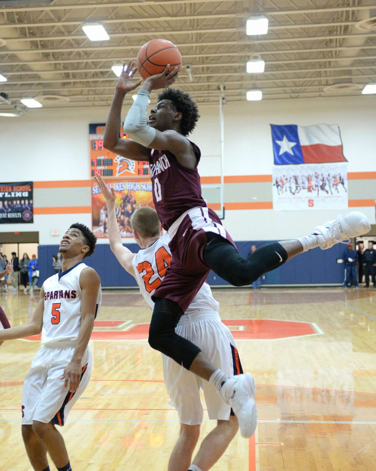 Jay Jay Chandler (0) of Cinco Ranch shoots past Jonathan Howell (24) and Logan West (5) of Seven Lakes during the first half of a boys basketball game between the Cinco Ranch Cougars and the Seven Lakes Spartans on Friday January 6, 2017 at the Seven Lakes HS, Katy, TX.