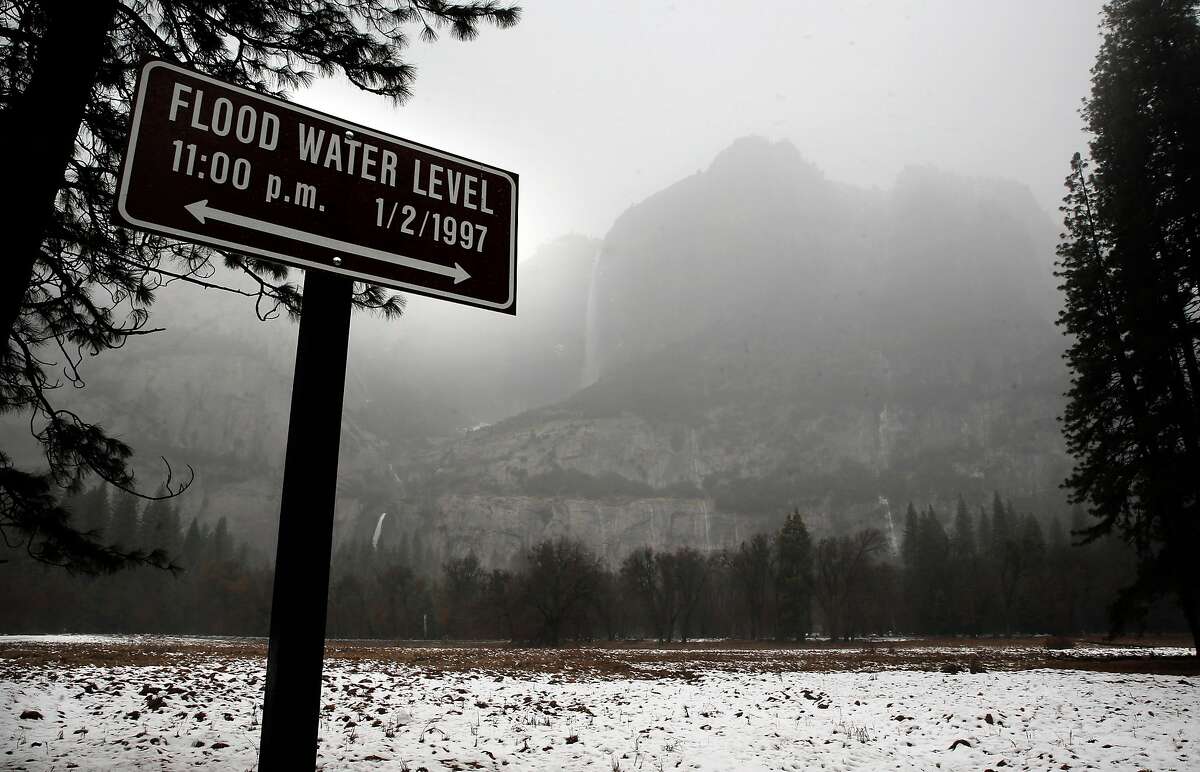 Yosemite Falls is seen behind a sign marking the waters level of the 1997 floods in Yosemite National Park, Ca., as seen on Saturday Jan. 7, 2017, as heavy rain begins to fall on the valley floor of the park.