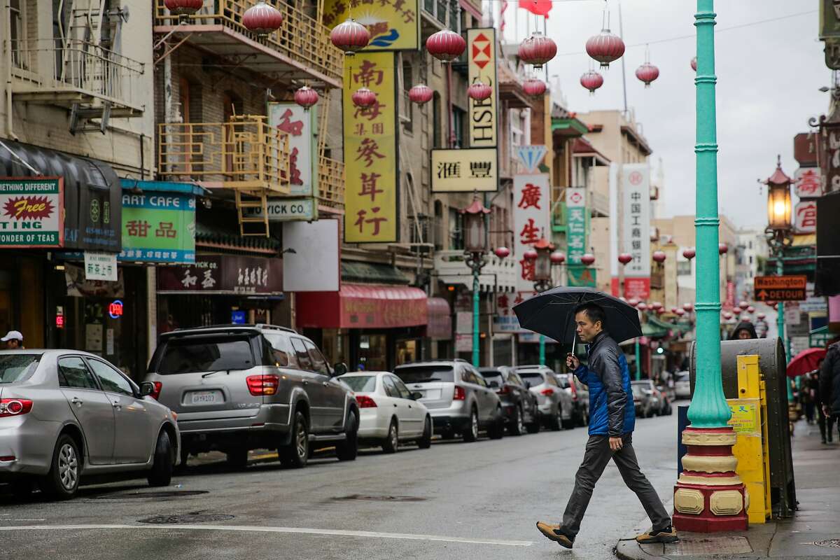 A man walks across Grant Street in Chinatown during a rainstorm in San Francisco, Calif., on Sunday, Jan. 8, 2017.