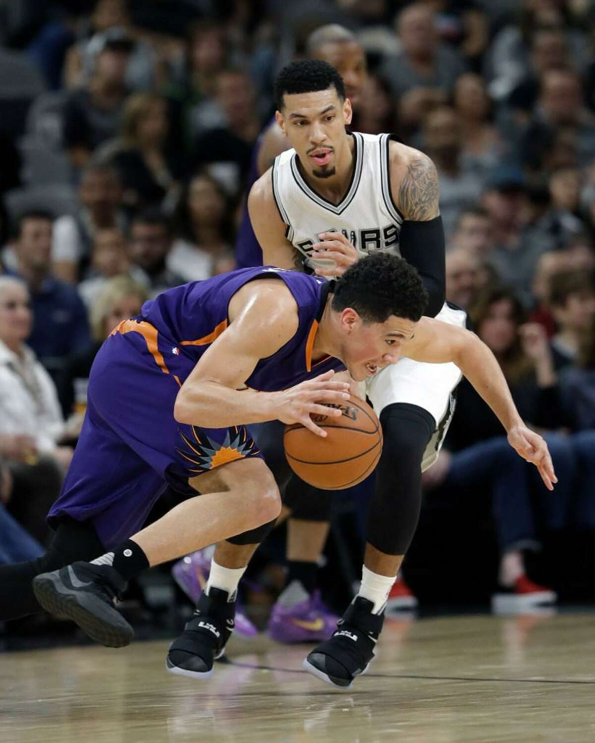 Phoenix Suns guard Devin Booker, front, drives around San Antonio Spurs guard Danny Green, rear, during the first half of an NBA basketball game, Wednesday, Dec. 28, 2016, in San Antonio. San Antonio Spurs won 119-98.