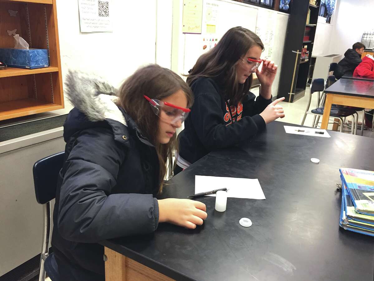 Lincoln Middle School seventh graders Jordan Baer, left, and Bailey Schuetz let their Alka-Seltzer tablets dissolve in a film canister.