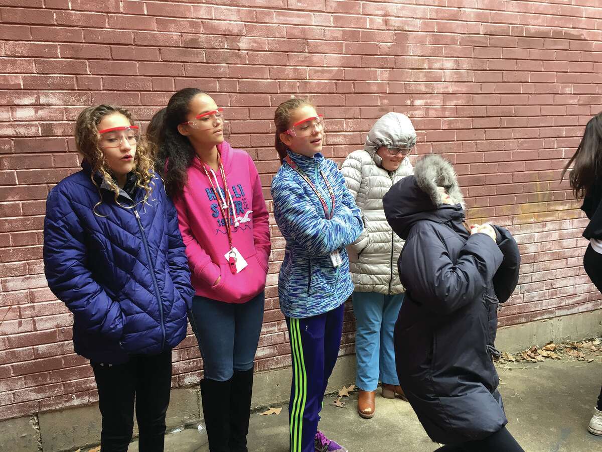 Lincoln Middle School seventh graders, from left, Sara Blandina, Ella Griffin, Sydney Lane, Sarah Slater, and, in front, Jordan Baer, wear eye protection as they watch their rockets – constructed from film canisters, Alka-Seltzer tablets and water – take off.