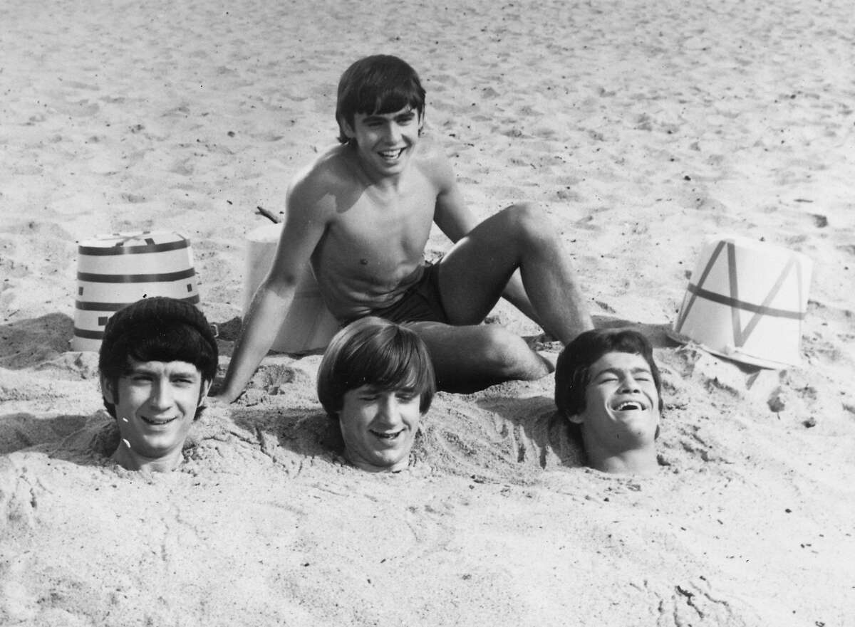 2nd February 1967: Three members of American pop group The Monkees have been buried up to their necks in sand by fellow group member Davy Jones. Buried members are, left to right, Mike Nesmith, Peter Tork and Micky Dolenz. (Photo by Keystone Features/Getty Images)